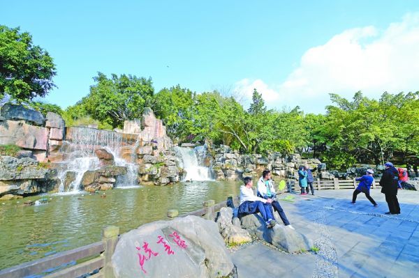 市民在南门坝生态公园景观瀑布旁休闲、“打卡”。